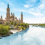 Scenery landscape with Basilica of Our Lady of Pillar. Blue sky reflects in clear water. Green trees along river. Famous church with beautiful architecture. Famous tourist place in Spain, Europe. i